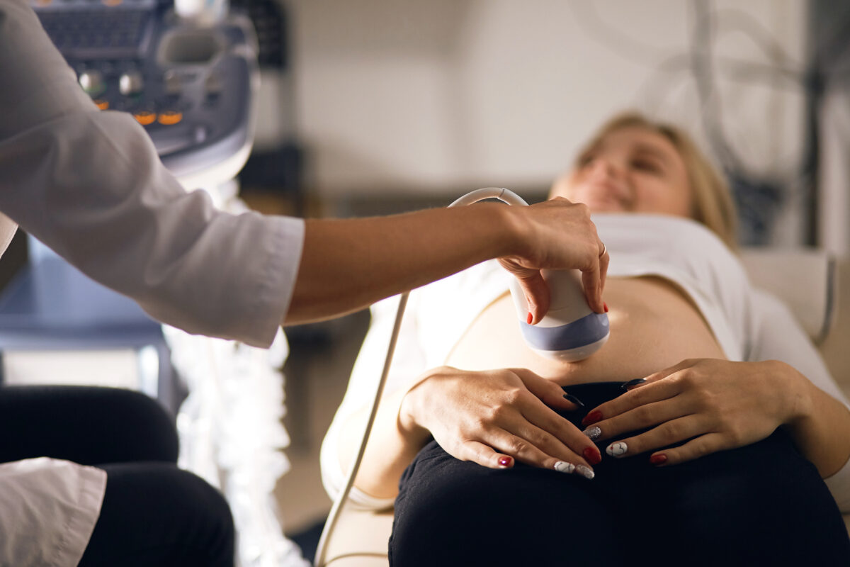 cheerful woman carriies a baby is being controlled by 4 D ultrasound machine